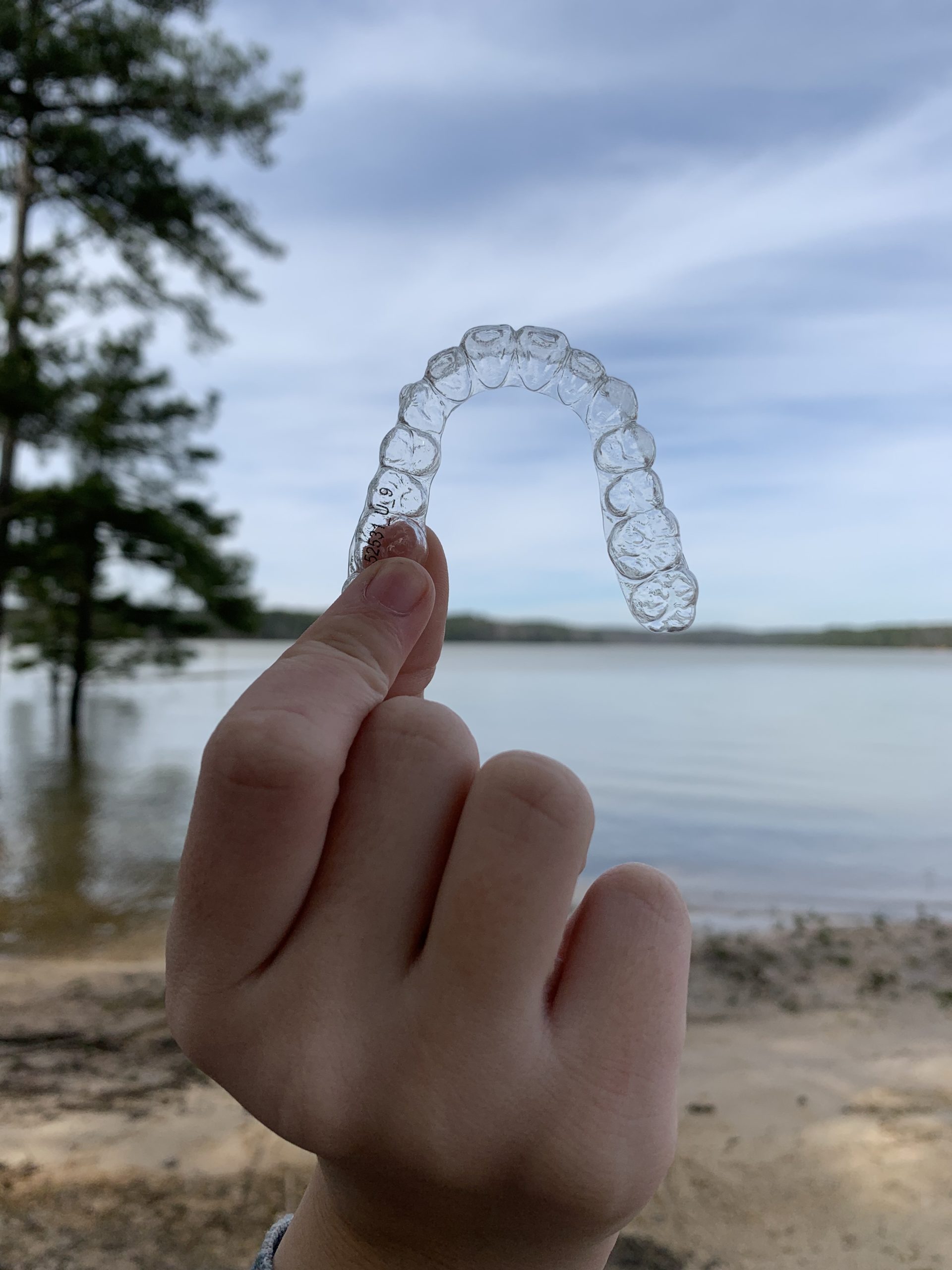 hand holding invisline braces by beach