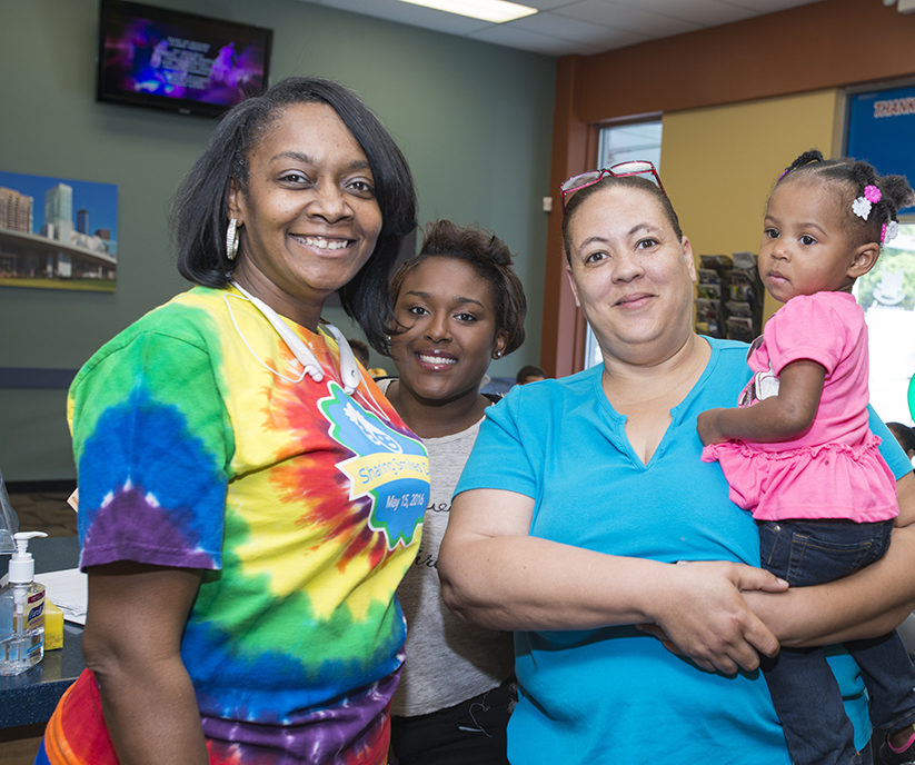group of mothers smiling while holding child